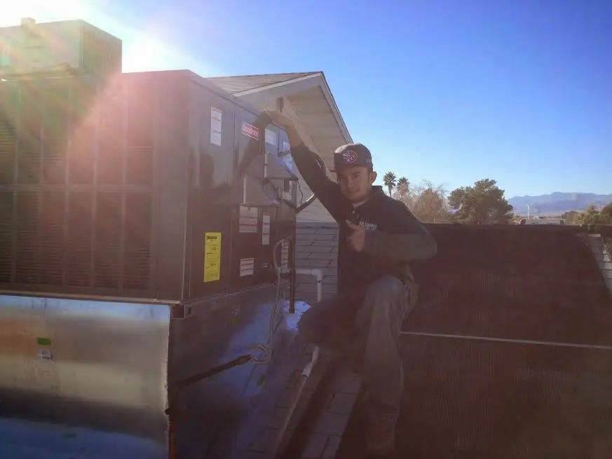HVAC technician performing Air Duct Cleaning on a rooftop unit in Newton